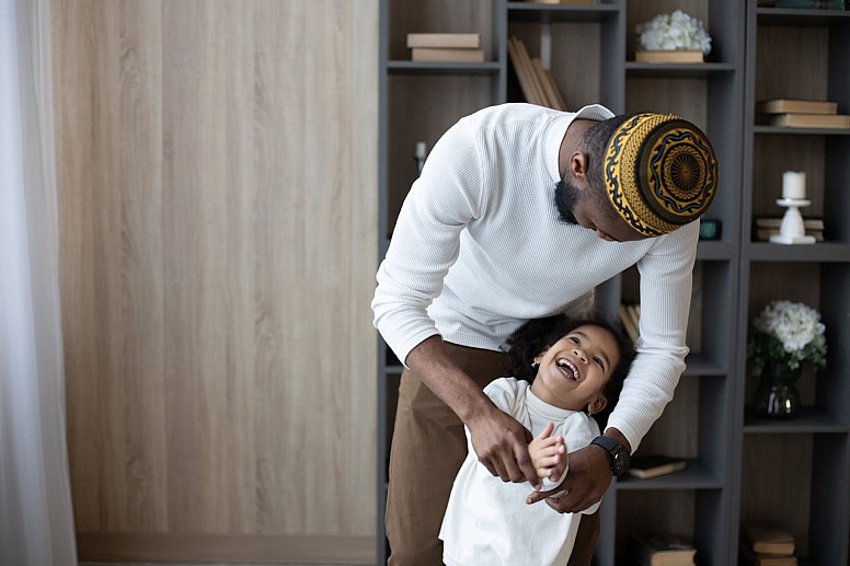 cheerful muslim father having fun with cute daughter